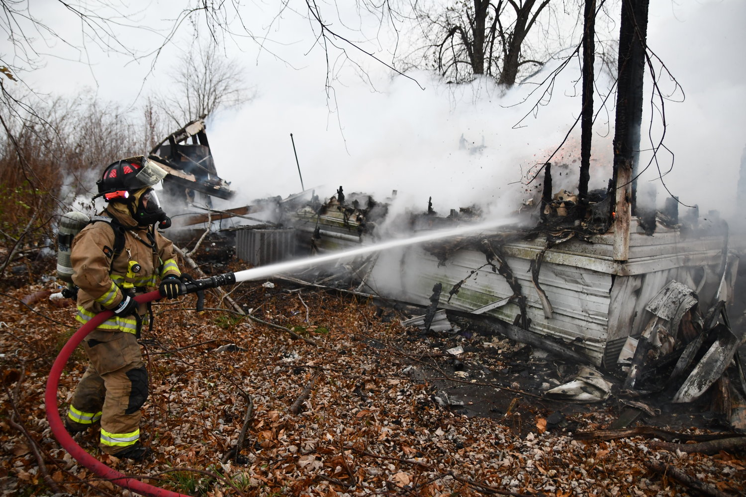 A FIREMAN extinguishes a hot spot Thursday morning on a fire which destroyed a rural Owensville man’s mobile home off of Farris Road. The man and his dogs had been sleeping in his truck which he said was cheaper to heat than the trailer unit. Volunteer firemen from several area departments and fire protection districts responded to the call on Thanksgiving for mutual aid manpower assistance at the site of the early-morning fire.