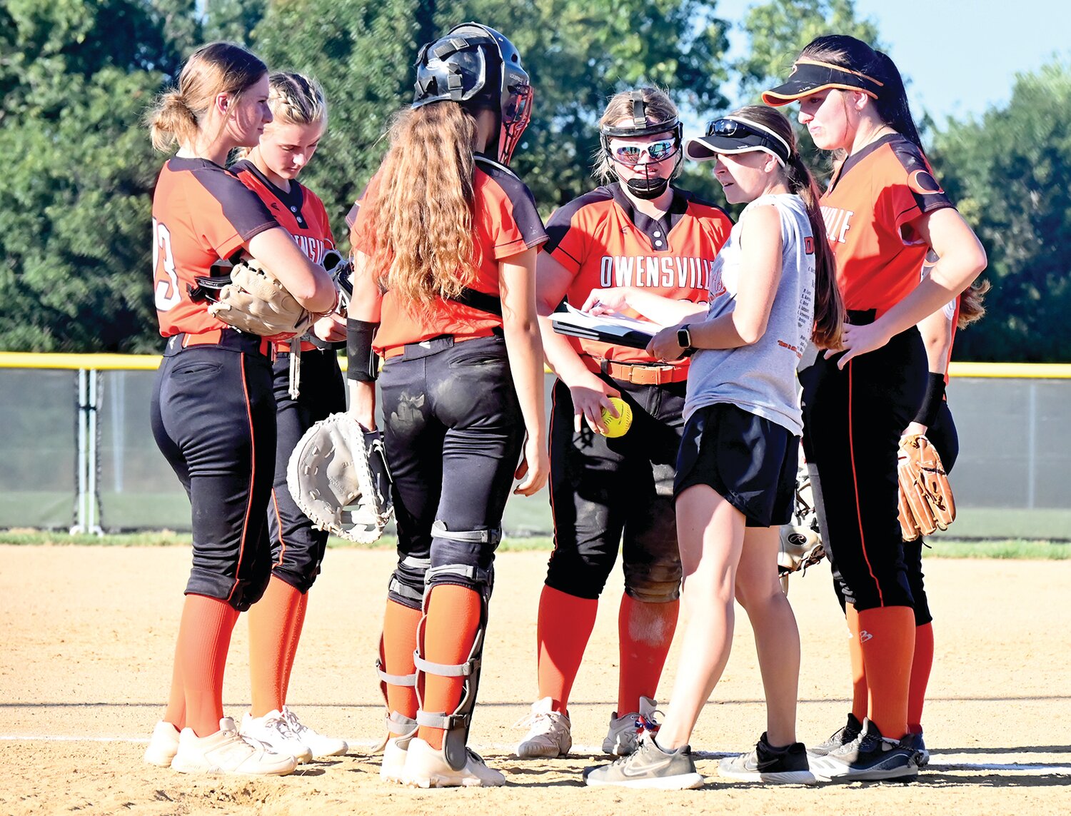 Owensville Dutchgirl head softball coach Hannah Koppelmann (white shirt) has a conference with her infielders during OHS’ 13-2 loss Thursday in Osage County at Linn.