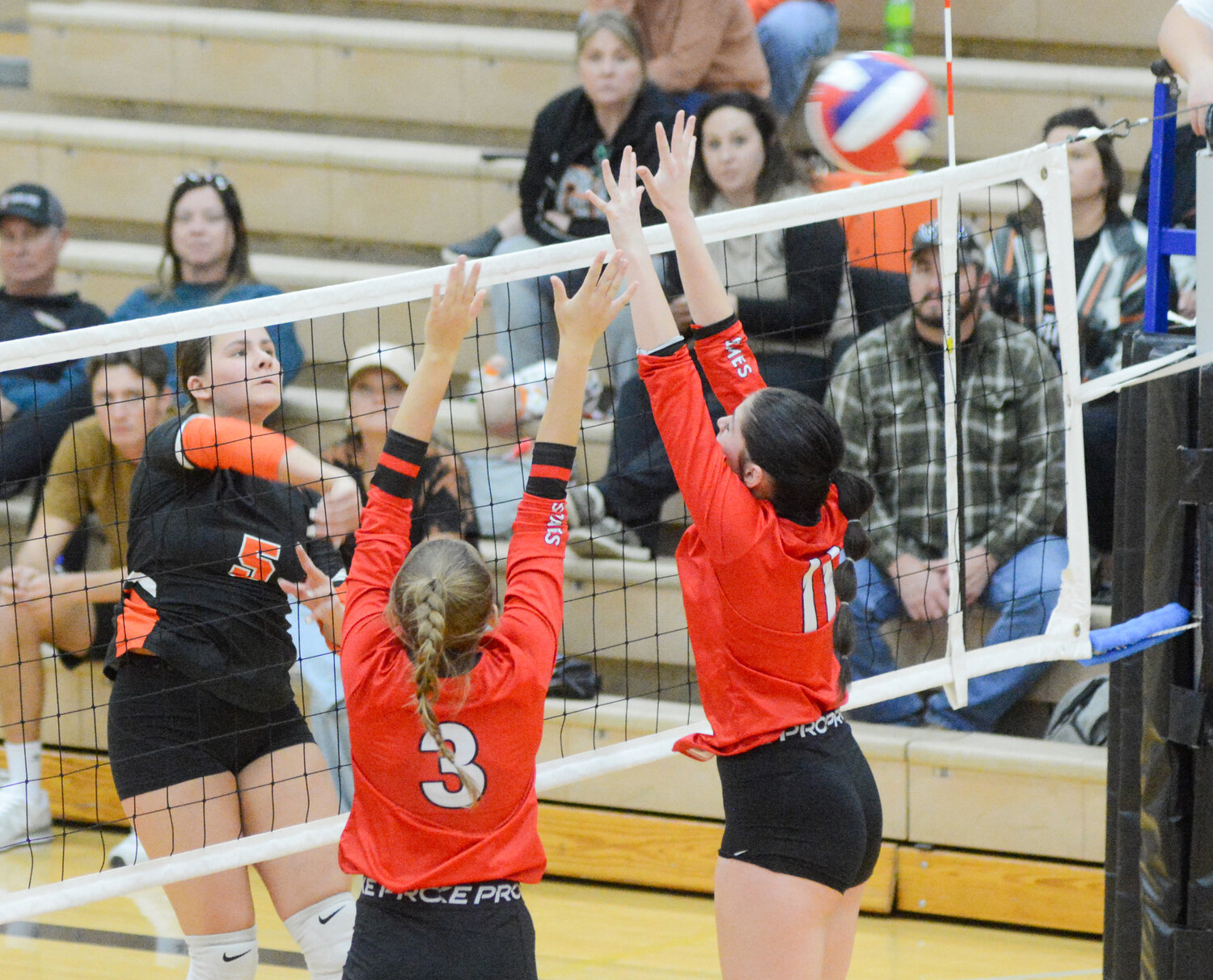 MCKENZY ECHOLS (far left) watches a spiked volleyball sail just over the net during home district volleyball action against St. James.